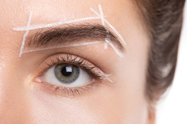 Close-up of a person's eye with white mapping lines drawn around the eyebrow for shaping accuracy.